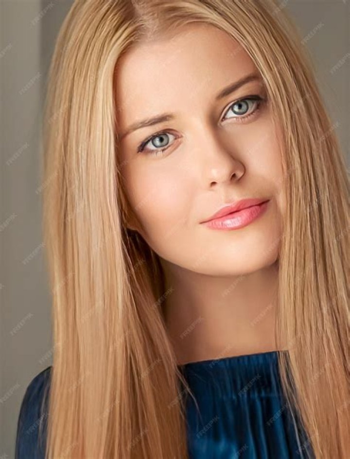 a woman with long blonde hair wearing a blue and white uniform smiling